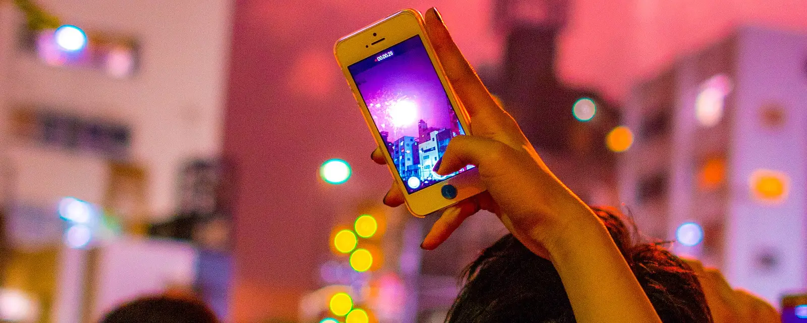 Raised smartphones recording fireworks over Asakusa at a summer festival