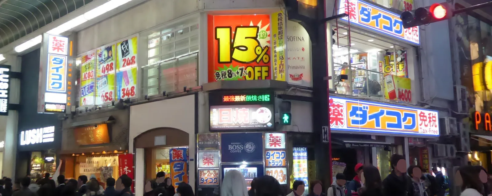 Neon pharmacy signs above a crowded Dotonbori street in Osaka at night