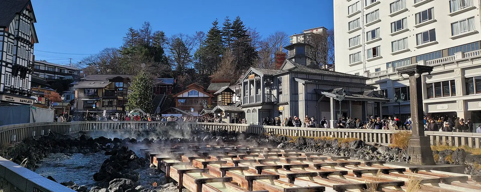 Steam rising from the wooden channels of Kusatsu Onsen's yubatake hot spring field