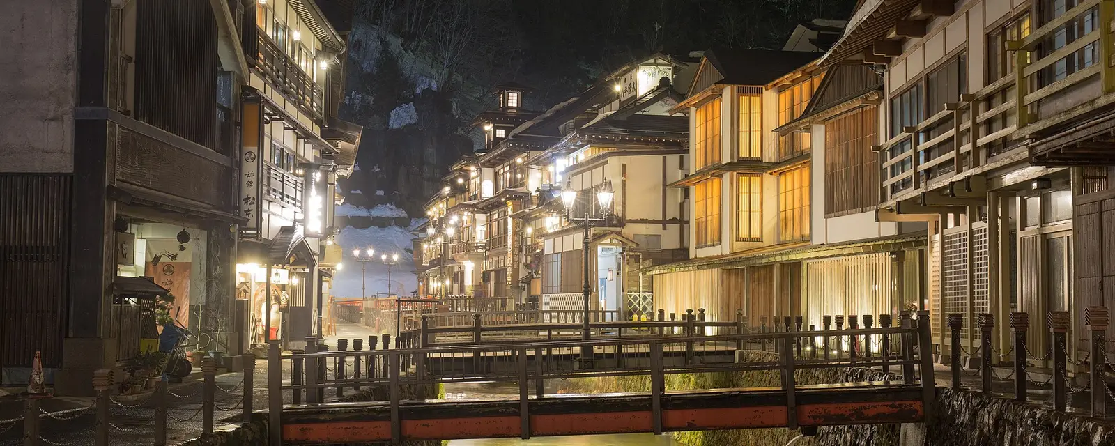 Lantern-lit wooden ryokan lining the river at Ginzan Onsen at night